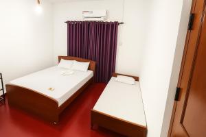 2 camas en una habitación pequeña con cortinas moradas en Premier Stay, en Chavakachcheri