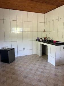 a kitchen with white tiled walls and a counter at Casa no sana in Macaé