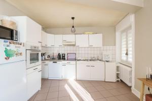 a kitchen with white appliances and a tile floor at Le Cocoon CléJa - Proche Station La Bresse in Ventron +4 photos