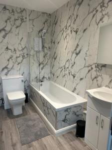 a bathroom with a tub and a toilet and a sink at Flat 2 in Hollinwood