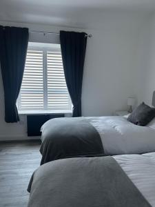 a bedroom with two beds and a window with blue curtains at Flat 2 in Hollinwood
