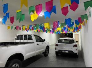 a white truck and a car parked in a room with flags at Pousada Açude Velho in Campina Grande