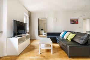 a living room with a black leather couch and a tv at CDT Duomo in Florence
