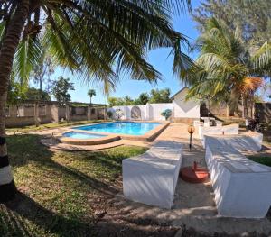 einen Pool im Garten mit Palmen in der Unterkunft kenda Villa 3 bedroom in Ukunda