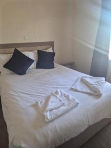 a white bed with blue pillows and towels on it at Sea Breeze Villa near to Newquay sleeping 6 guests in Newquay +7 photos