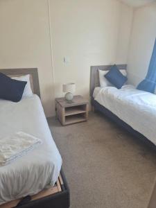 a bedroom with two beds and a nightstand between them at Sea Breeze Villa near to Newquay sleeping 6 guests in Newquay