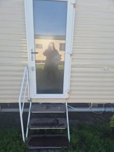 a woman standing at the door of a house at Sea Breeze Villa near to Newquay sleeping 6 guests in Newquay
