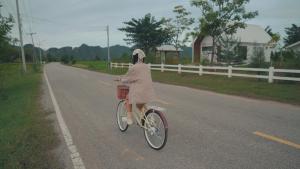 a woman riding a bike down a road at West Mount Cafe & Restaurant in Ban Hua Hin