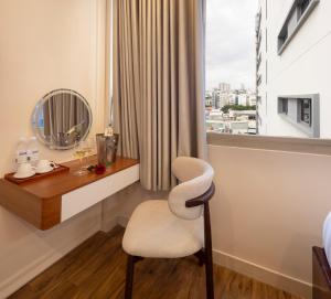 a room with a chair and a window with a mirror at SCAT Hotel- New World Bến Thành in Ho Chi Minh City