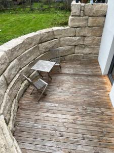 a wooden deck with a bench and a stone wall at Rufus' Bergblick in Bernau am Chiemsee
