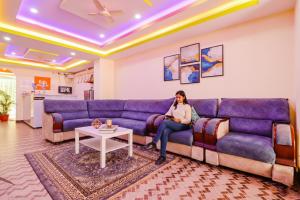 a woman sitting on a couch in a living room at FabHotel Broholic Suites - Nr JNTU in Hyderabad