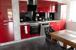 cocina con armarios rojos y mesa de madera en NEU! Ferienhaus Mein Geestland, en Imsum