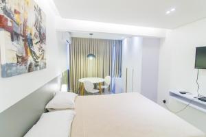 a white room with a bed and a table at Flat central, charmoso e confortável - 804 Garvey in Brasilia