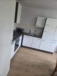 una cucina con mobili bianchi e pavimento in legno di Haus Sonnenschein a Dornum