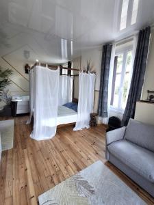 una stanza con un letto con tende bianche e un divano di Le Bali Zen a Charavines Altre 4 foto