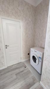 a laundry room with a washing machine and a door at Квартира с хорошей аурой in Almaty