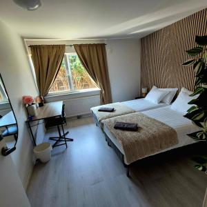a bedroom with two beds and a desk and a window at SO Easy Stay, Malmö in Malmö