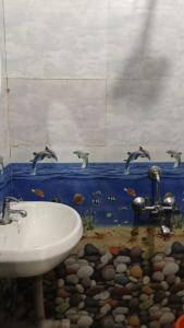 baño con lavabo y pájaros en la pared en Supriya holiday in, en Corgao