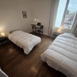 トノン・レ・バンにあるAppartement de charme au cœur de Thononのデスク、窓が備わるドミトリールームのベッド2台分です。