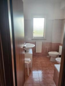 a bathroom with a sink and a toilet and a window at Villetta Magnolia in Giardini Naxos +6 photos
