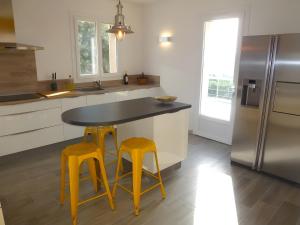 a kitchen with a black counter and two yellow stools at Villa Luxe – Vues panoramiques in Volx