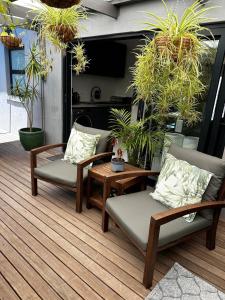 un patio con 2 sedie, un tavolo e piante in vaso di Green Oasis in Blouberg Hot Tub Kids Paradise a Città del Capo