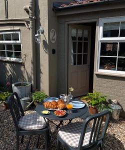 - une table avec une assiette de pain et des fruits dans l'établissement Worstead Cottage by Big Skies Cottages, à Worstead