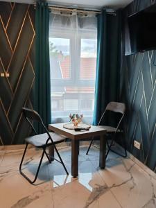 une table et deux chaises dans une pièce avec une fenêtre dans l'établissement Le petit Tagidor - 5 suites - 2 kitchens - 5 bathrooms, à Charleroi