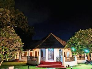 阿勒皮Anna's Heritage bungalow的晚上，外面有红色楼梯的小房子