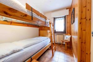 a bedroom with two bunk beds and a chair at Cesa Alpes 3 in Campitello di Fassa