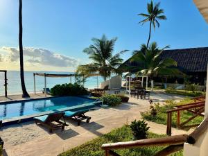 a swimming pool next to the beach with palm trees at AVO Boutique Hotel in Dikoni
