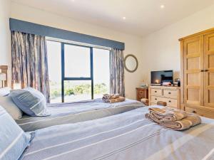 Dos camas en un dormitorio con una gran ventana. en 2 Bed in Helston oc-s33457, en Ruan Major