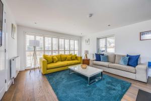 ein Wohnzimmer mit einem gelben Sofa und einem Tisch in der Unterkunft Sundowner - West Wittering in East Wittering