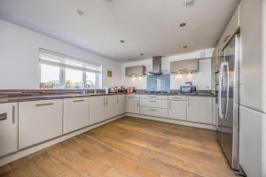 eine Küche mit weißen Schränken und einem Holzboden in der Unterkunft Sundowner - West Wittering in East Wittering + 37 Fotos