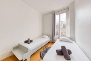 una stanza bianca con due letti e una finestra di L'Haussmannien 2BR aux portes Paris - 2 min Métro a Clichy