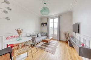 un soggiorno con un divano e un tavolo di L'Haussmannien 2BR aux portes Paris - 2 min Métro a Clichy