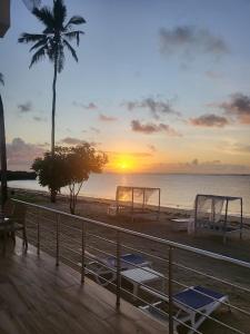 a beach with tables and a palm tree and the sunset at Kilifi Pearl Beach Resort in Kikambala