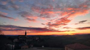 a sunset over a town with a church on a hill at Les Raspes du Samphy in Saint-Victor-et-Melvieu