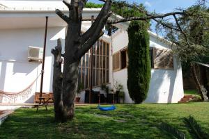 a white house with a tree in the yard at Casa familiar en la playa con piscina in Teià