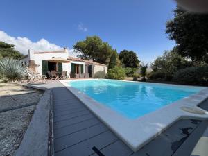 a swimming pool in front of a house at Villa de l Olivaie in Les Grenettes