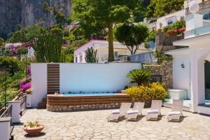 Un grupo de sillas en un patio con un banco. en Villa La Baika by MyVillaCollection, en Capri