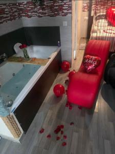 a bathroom with a tub and a red chair with roses on the floor at Loft "Coqueto" Rojo in Ubrique