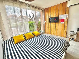 a bedroom with a bed with yellow pillows and a window at Appartement * Palavas-les-flots * Piscine in Palavas-les-Flots