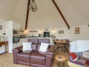 a living room with a leather couch and a table at Yr Awen - Inspiration in Cribyn