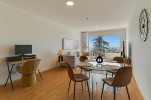 Una sala de estar con una mesa y sillas y un televisor. en Sun Flower, en Caniço