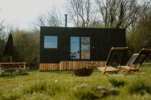 a black tiny house with two chairs and a table at Altair in Holywell +10 photos