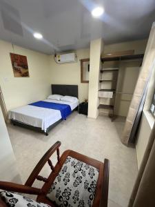 Un pequeño dormitorio con una cama y una silla. en A pasos del mar y centro de Puerto Colombia, en Puerto Colombia