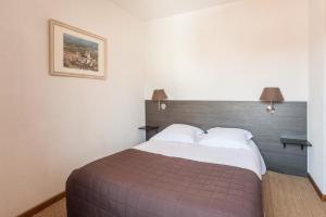 a bedroom with a large bed with a wooden headboard at Le Relais Des Dix Crus - Logis Hôtel B&B in Corcelles-en-Beaujolais