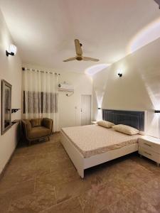 a bedroom with a bed and a chair and a ceiling fan at Apartment in Karachi near airport in Karachi
