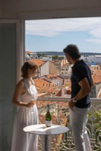 un hombre y una mujer de pie en un balcón con vistas a una ciudad en Hotel Renoir, en Cannes